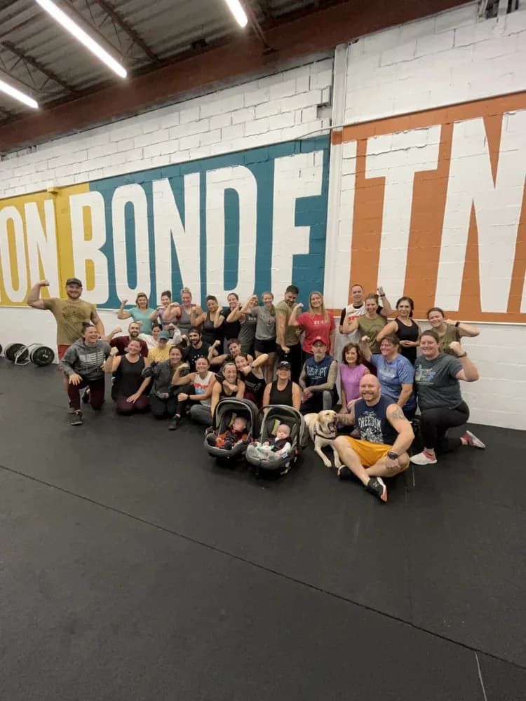 A big group of members flexing in front of the painted studio mural